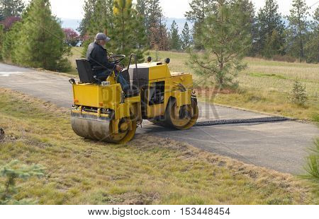 Colbert, WA - October 24, 2016: Workers of Black Diamond Asphalt Paving, LLC., repairing patches in a private road/driveway