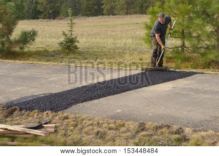 Colbert, WA - October 24, 2016: Workers of Black Diamond Asphalt Paving, LLC., repairing patches in a private road/driveway