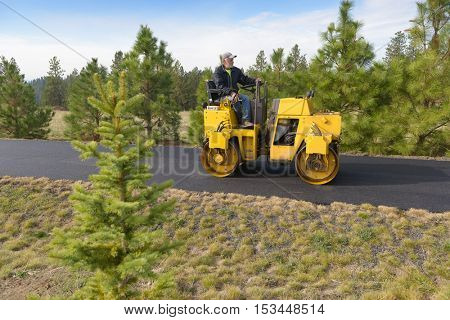 Colbert, WA - October 24, 2016: Workers from Black Diamond Asphalt Paving, LLC., repairing patches and re-paving a private road/driveway