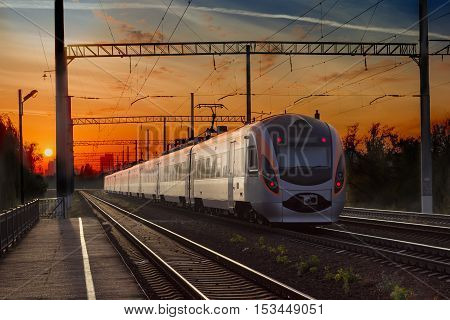 Leaving high-speed inter-city train in the city on the sunset background