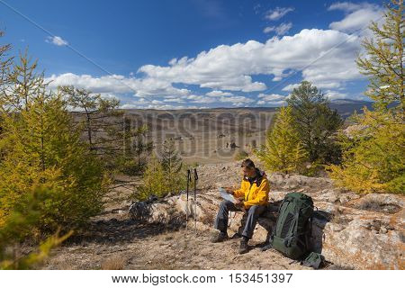 Man tourist backpacker reading map on forest trip while resting. Man hiker searching looking for direction guide. Backpacking summer vacation adventure..