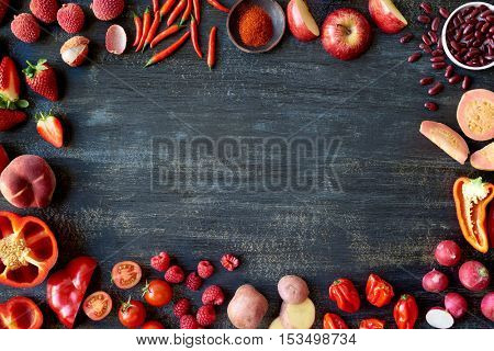 Food border frame made from red coloured fruits and vegetables, produce design poster with copy space
