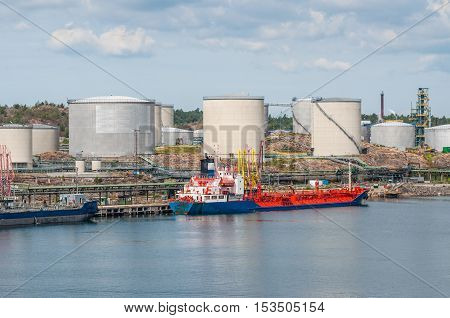 Tanker unloading with oil storage tanks in the background