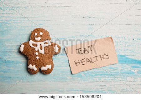 Eat healthy New Year resolution, gingerman and message on vintage wooden background