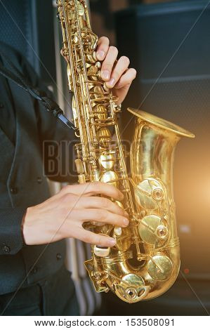 Musical instrument saxophone close-up. Hands on a musical instrument. Young guy playing jazz.