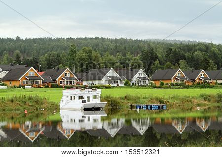 houses along the lake with gray metal roofs reflected in the water Scandinavia