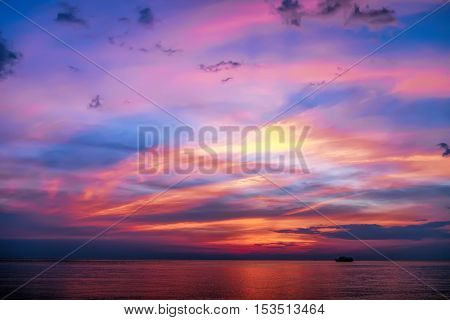 Tropical colorful dramatic sunset with cloudy sky and silhouette of the ship on the horizon. Evening calm on the Gulf of Thailand. Bright afterglow.