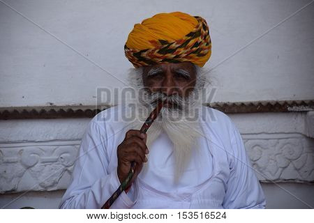 JODHPUR, RAJASTHAN, INDIA - FEBRUARY 10, 2016 - Portrait of an unidentified indian man smoking opium from a pipe inside Jodhpur fort