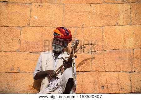 JAISALMER, RAJASTHAN, INDIA - FEBRUARY 10, 2016 - Portrait of an unidentified aged indian man with white beard playing a traditional string instrument outside Jaisalmer fort