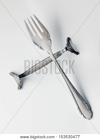 Close-up of victorian silver fork on silver knife rest. On white background