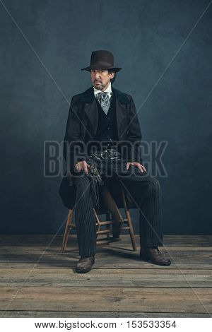 Vintage 1900 Western Mature Man With Revolver Sitting On Wooden Stool.