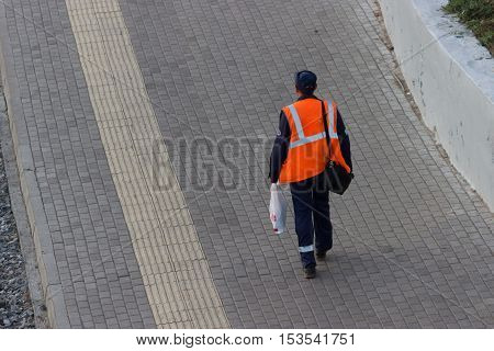worker in orange uniform walking along the street