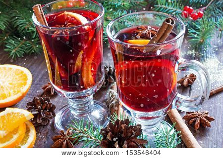 hot christmas mulled wine with snow cinnamon sticks anise and orange on wooden table background with fir branches and pine cones
