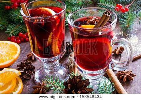 hot christmas mulled wine with cinnamon sticks anise and orange on wooden table background with fir branches and pine cones