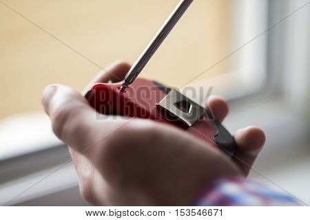the young man unscrews the screw with a screwdriver