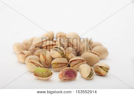 Heap of dry salted pistachio fruit on white background