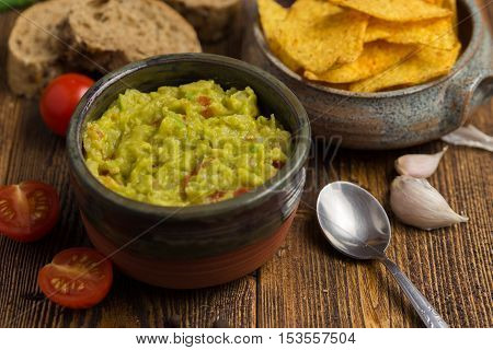 Guacamole in home crafted bowl on natural wooden desk.