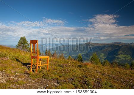 Old wooden chair on the top in Gerlitzen Apls in Austria.View of the mountains in Slovenia.