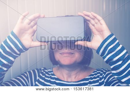 Woman watching 360 video with virtual reality headset. Female using VR goggles to enjoy futuristic multimedia content that simulates physical presence and allows interaction with environment.