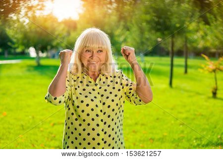 Smiling woman with raised fists. Happy senior lady. Small victories every day. Cheerful and energetic.