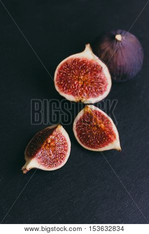 figs on a dark wood background. tinting. selective focus on the front figs slice in the bowl