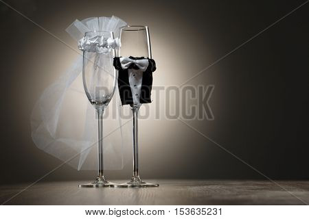 Elegant champagne glasses dressed in mini suitsof bride and groom