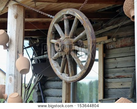 Obsolete old wheel of the horse cart. Hanging under the roof of a rural hut. Retro. Closeup. Ural, Russia.