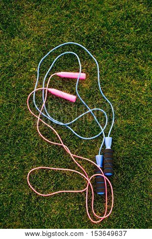 Jump ropes on grass. Pink and blue skipping ropes. How to train cardiovascular system. Agility and endurance.