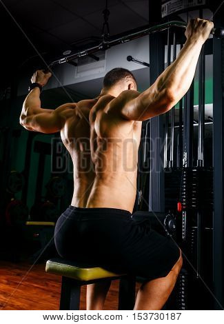 very power athletic guy bodybuilder, execute exercise with gym apparatus, on broadest muscle of back