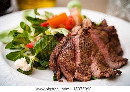 Entrecote with green salad and vegetables served on a white plate