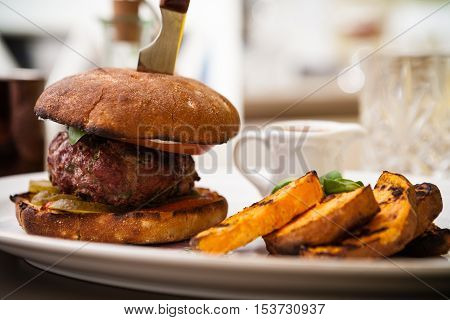 Beefburger with fried sweet potatoes served on a white plate