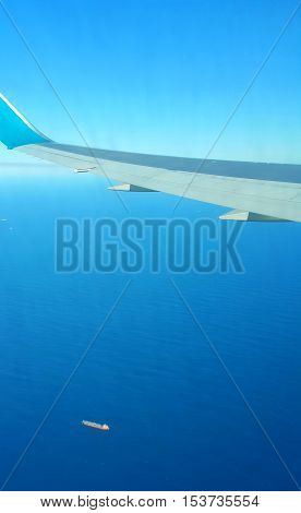 Airplane Wing Over Blue Sea with Ship Below