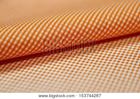 close up roll orange and white scott pattern fabric of shirt photo shoot by depth of field for object