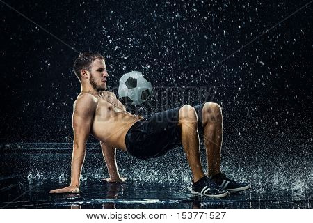 Water drops around football player on black background