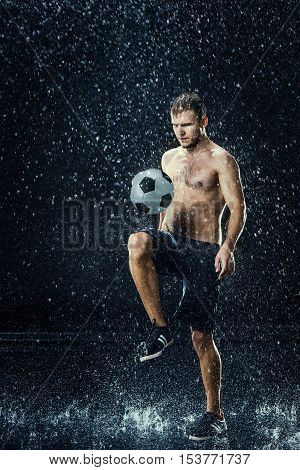Water drops around football player on black background
