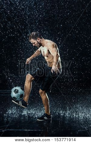 Water drops around football player on black background