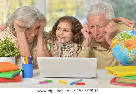 Portrait of happy grandparents  and a little girl using laptop