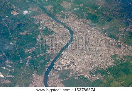 aeral shot of a small town with river flow across and green fiels around