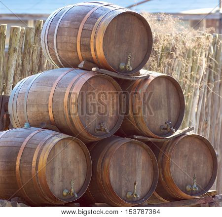 wooden wine barrels kegs stacked in pyramid outside cellar
