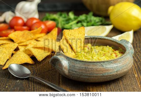 Guacamole in white bowl on natural wooden desk.