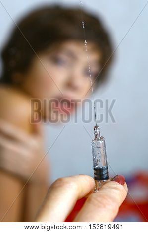doctor holding a syringe with injection vaccination. Boy is afraid. Teen boy in fear of injection.