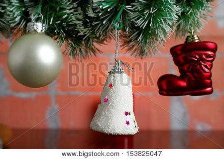 hanging Christmas baubles on the artificial spruce twig against brick wall