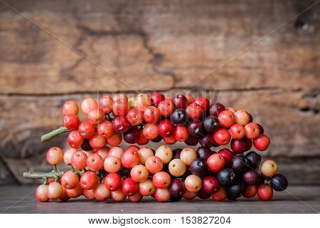 thai blueberry on wooden background, (Antidesma thwaitesianum)