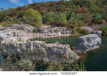 At the foot of the hill on which La Roque sur Cèze in France lies swirl spectacular waterfalls and rapids of the Cascades du Sautadet.