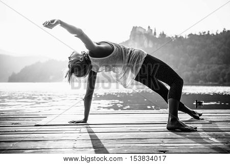 woman practicing yoga by the lake, black and white image