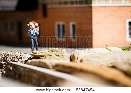 Small hiker figure walking with backback in city.