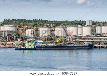 Tanker unloading with oil storage tanks in the background