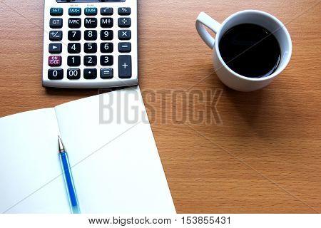 Notebook with pen calculator with white cup of coffee