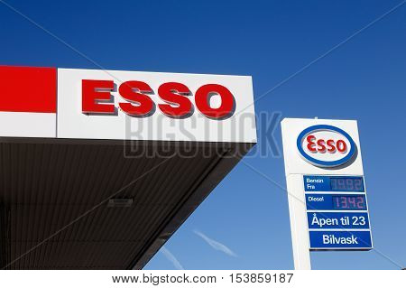 Elverum Norway - October 3 2016: Detail of an Esso gasoline service station roof with an advertising sign on a pole with logo and prices.