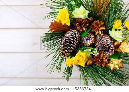 Christmas background with yellow silk roses and golden pine cones. Christmas party decoration. Christmas greeting background. Copy space.